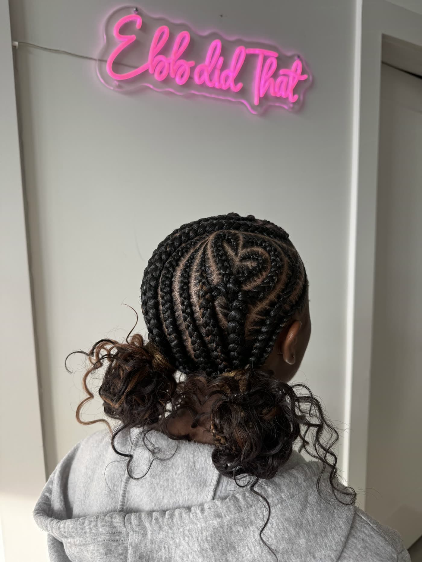 Intricate stitch cornrow pattern braided into a low curly bun