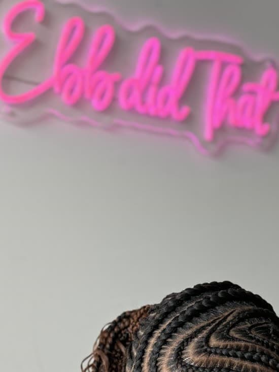 The pink neon Ebb did That sign above a fresh set of stitch feed-in cornrows